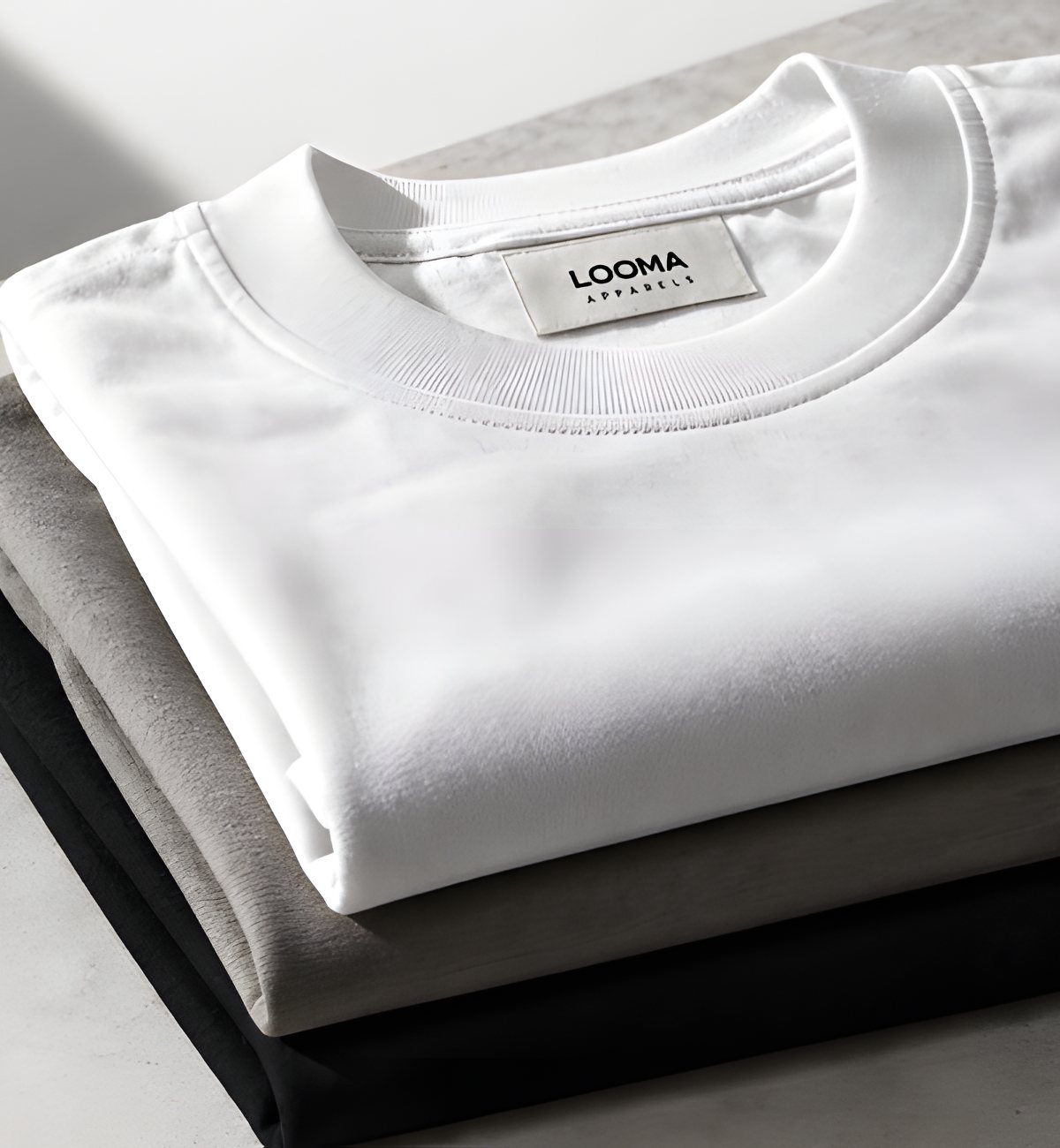 Folded Looma t-shirts in white, grey and black